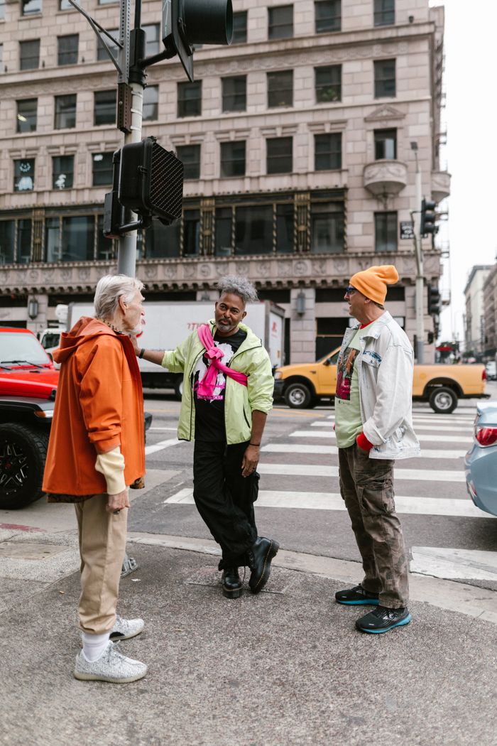 Stylish senior adults chat on a city street corner in fashionable outfits.