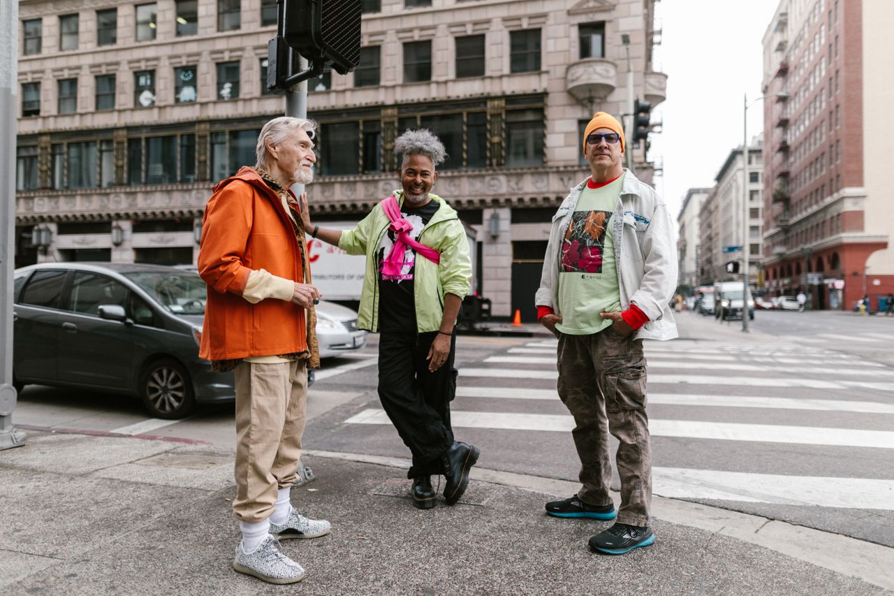 Three senior men showcase unique street fashion on an urban city corner, embodying friendship and style.